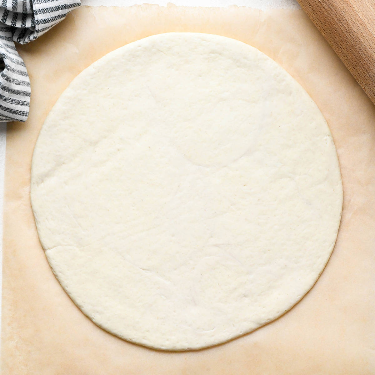 pizza dough rolled into a circle on a piece of parchment paper