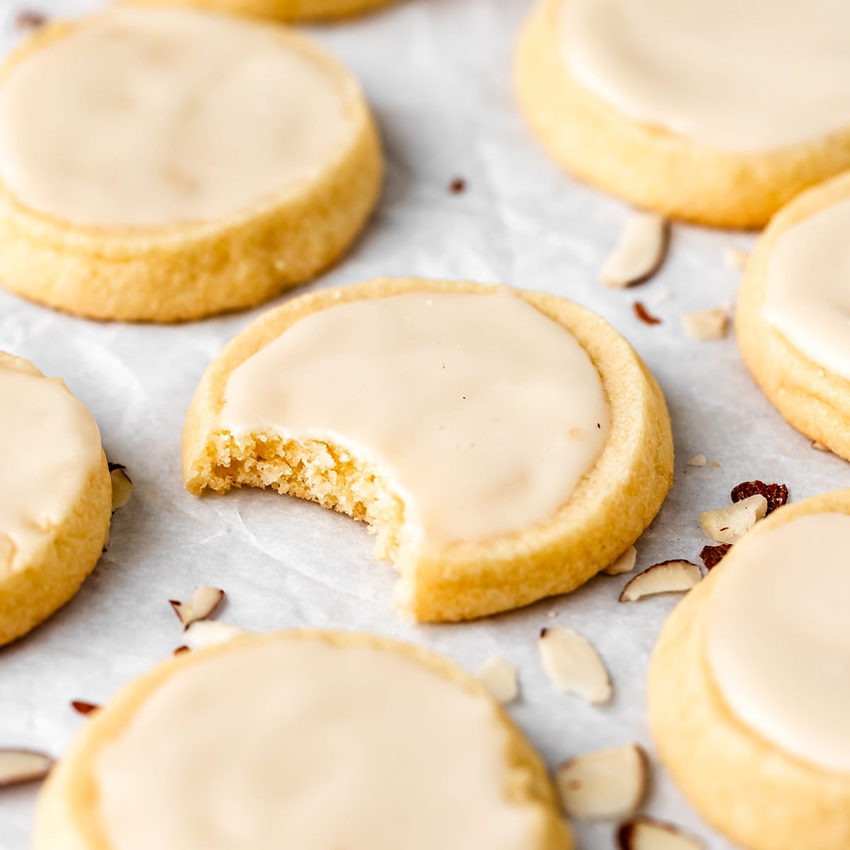 7 Almond Cookies with glaze, one with a bite taken out of it