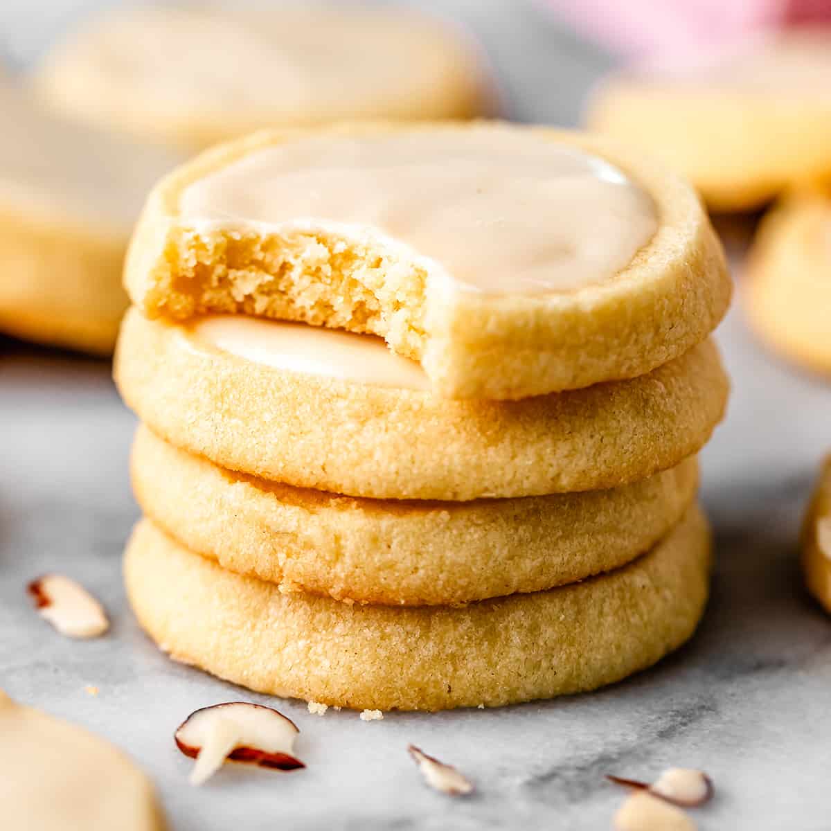 a stack of 4 Almond Cookies with glaze, the top one has a bite taken out of it