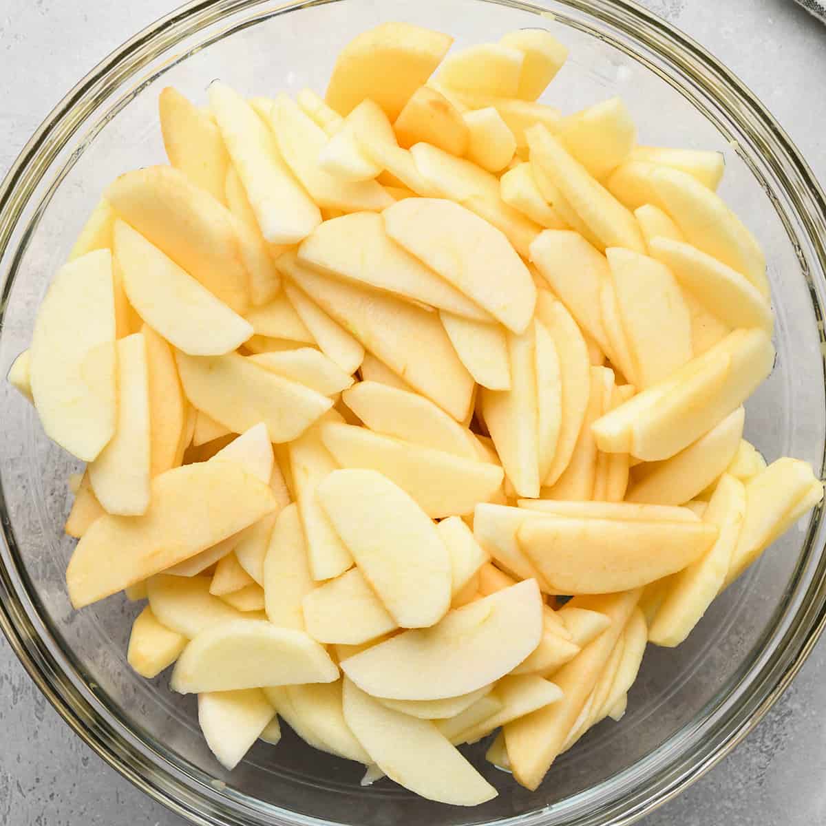 peeled and sliced apples in a glass bowl