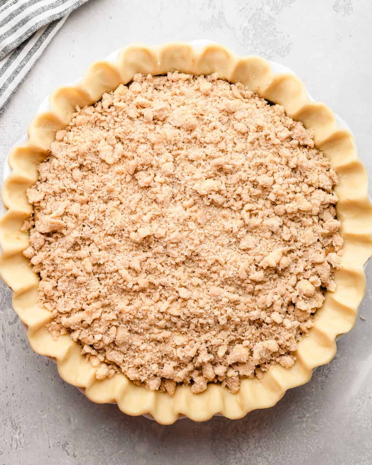 assembled apple crumble pie with a fluted pie crust and a crumb topping