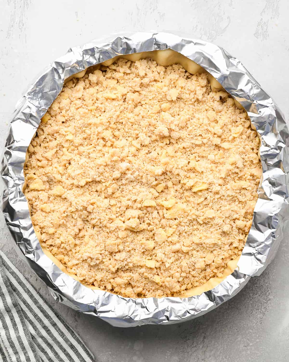 apple crumble pie with a pie crust shield before baking