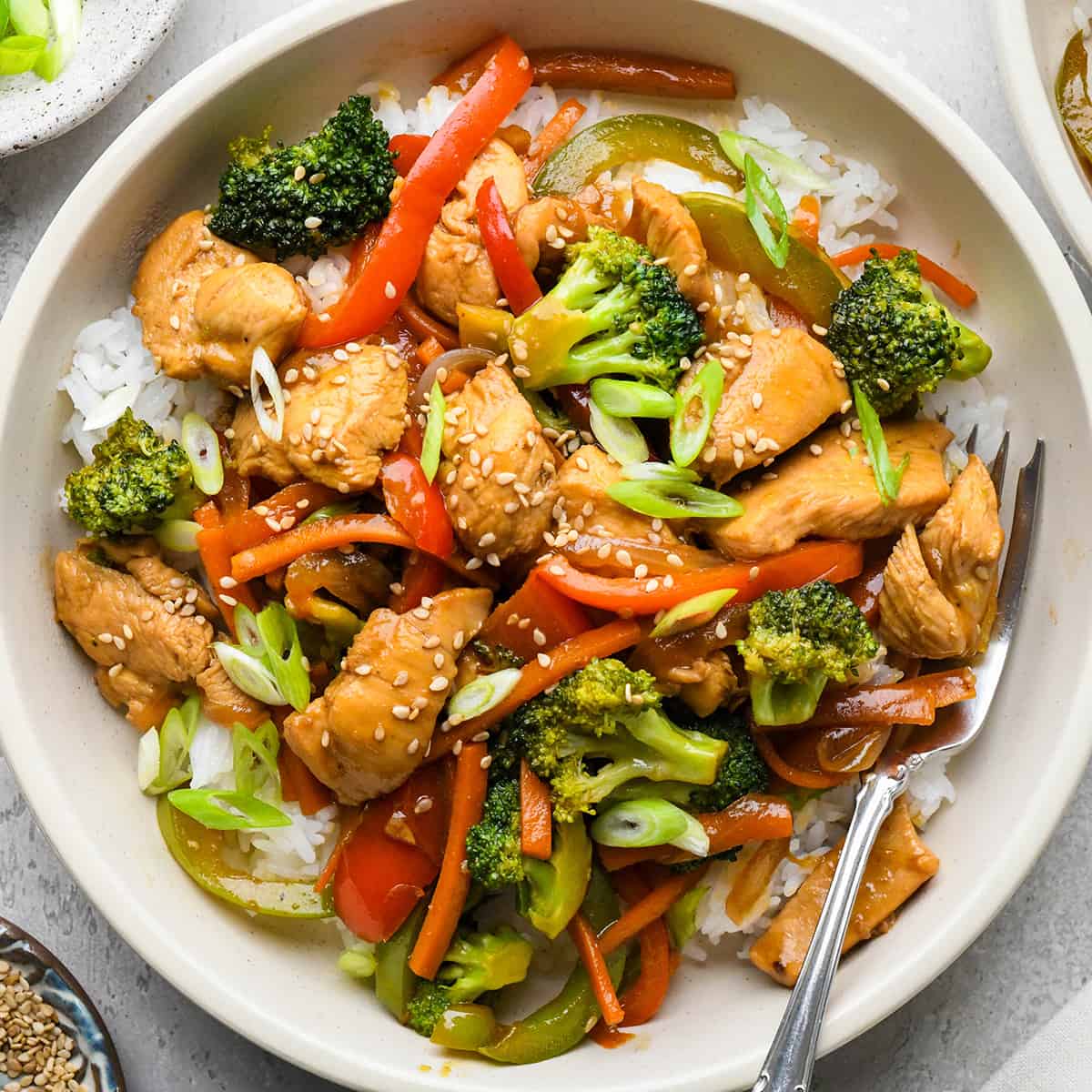 Chicken Stir Fry over rice in a bowl with a fork