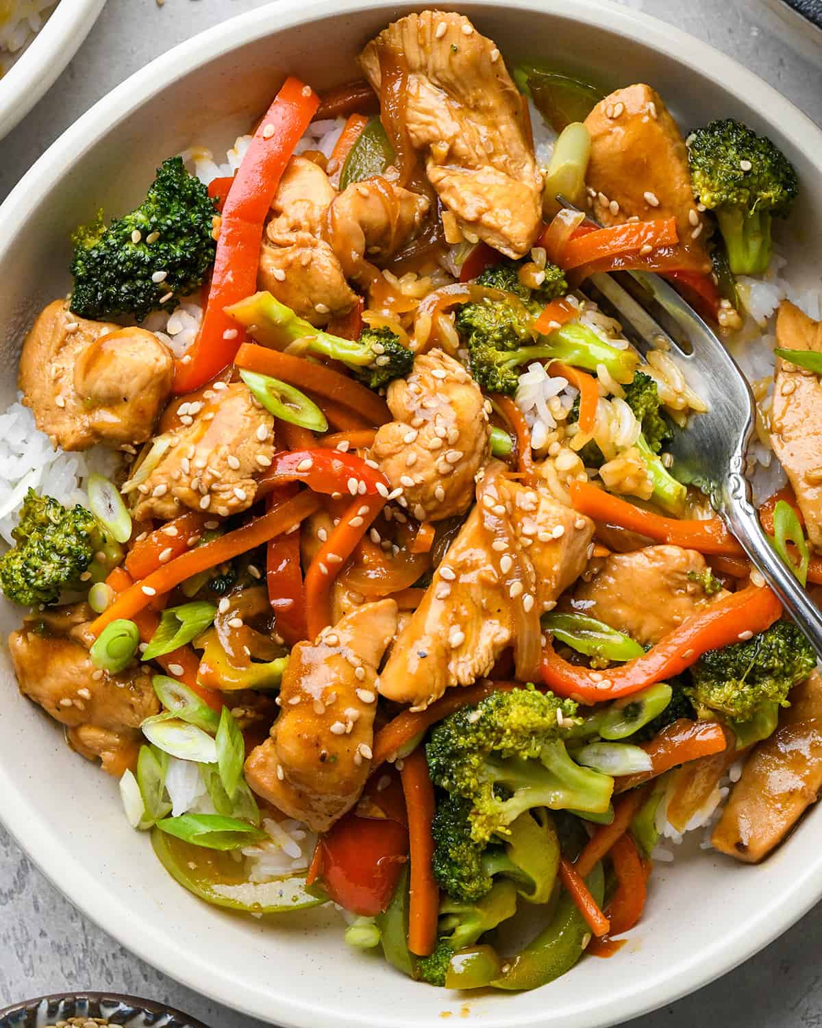 Chicken Stir Fry over rice on a plate with a fork