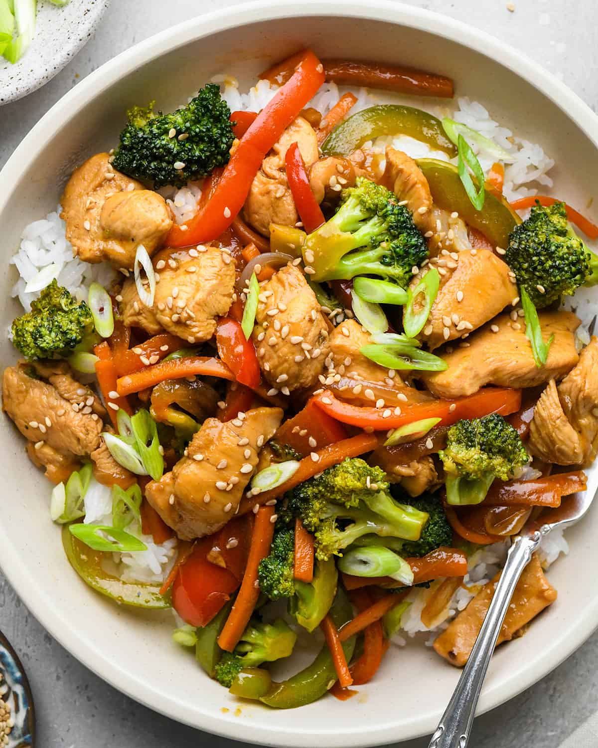 Chicken Stir Fry over rice in a bowl with a fork