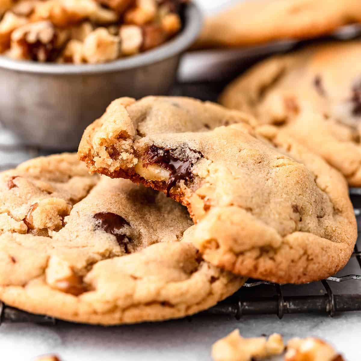 two Chocolate Chip Walnut Cookies, one with a bite taken out of it