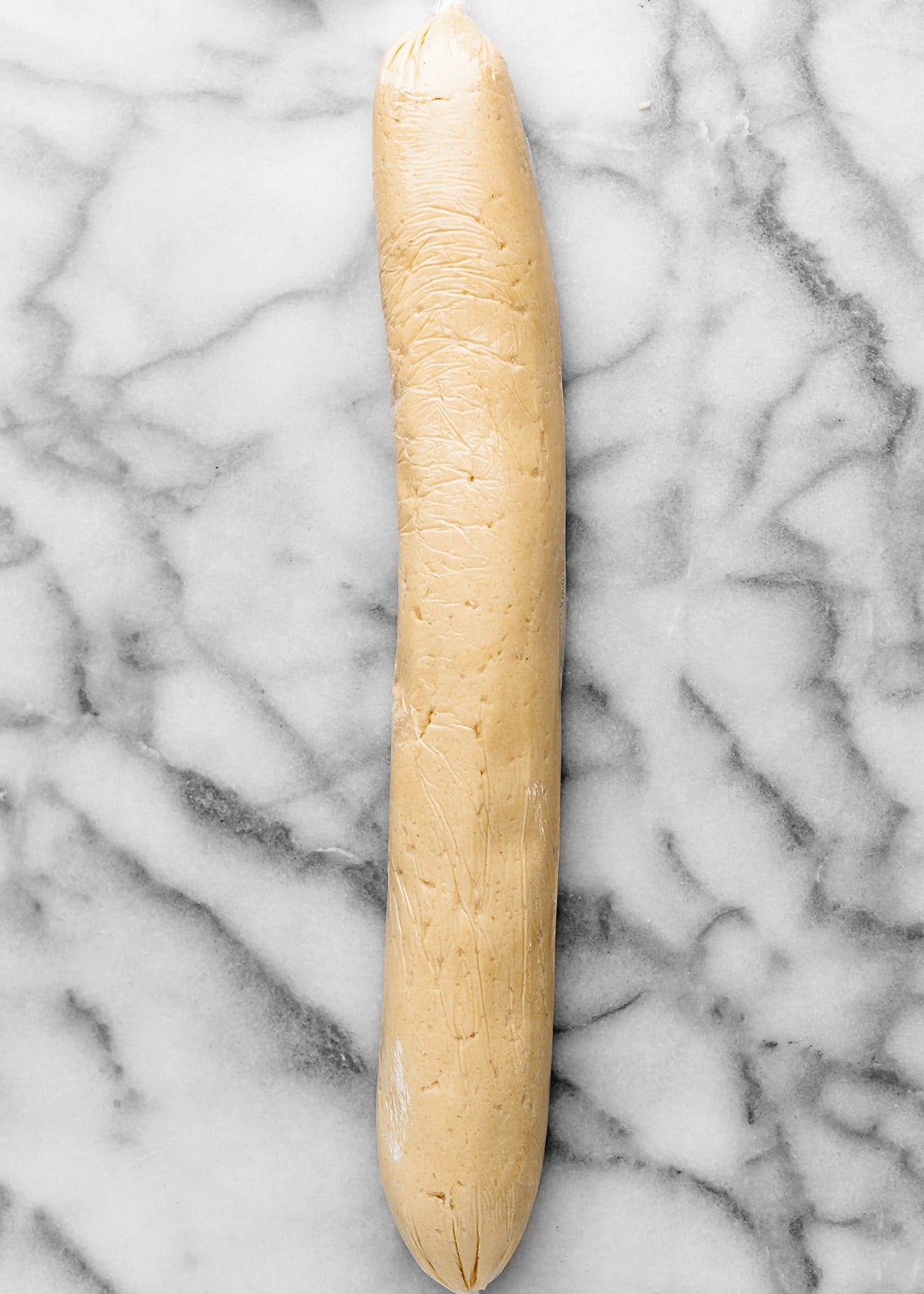 almond shortbread cookies dough rolled into a log and wrapped in plastic wrap