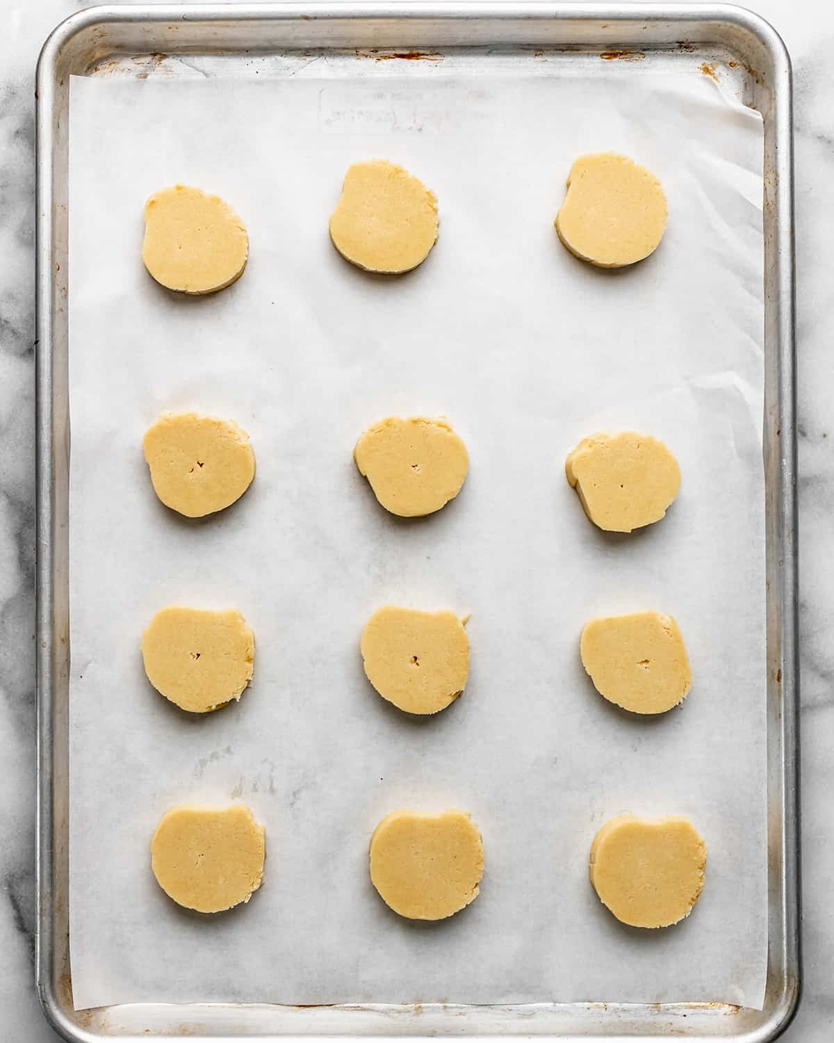 12 almond shortbread cookies on a baking sheet before baking