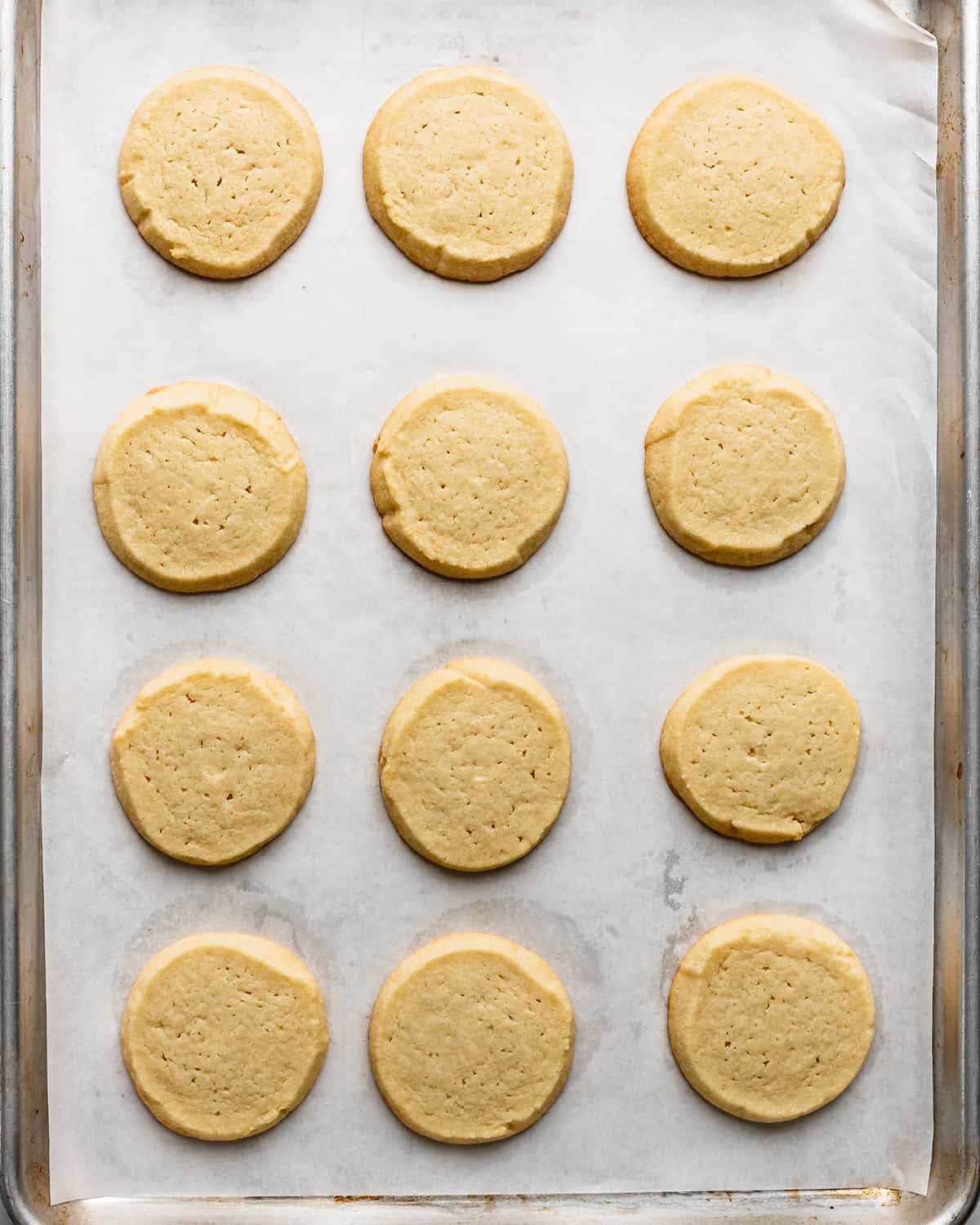 12 almond cookies on a baking sheet after baking