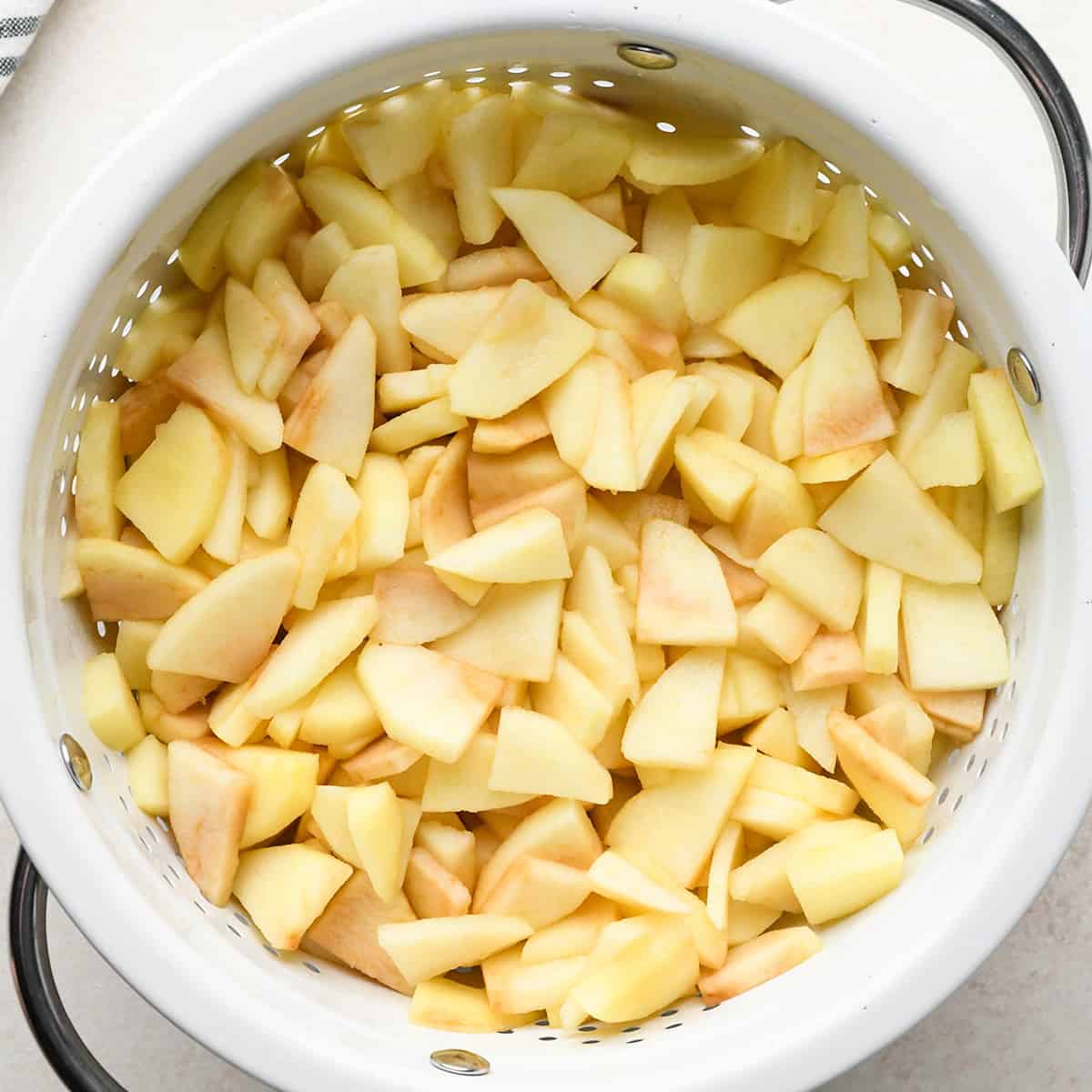 apple slices draining in a colander to make apple crisp