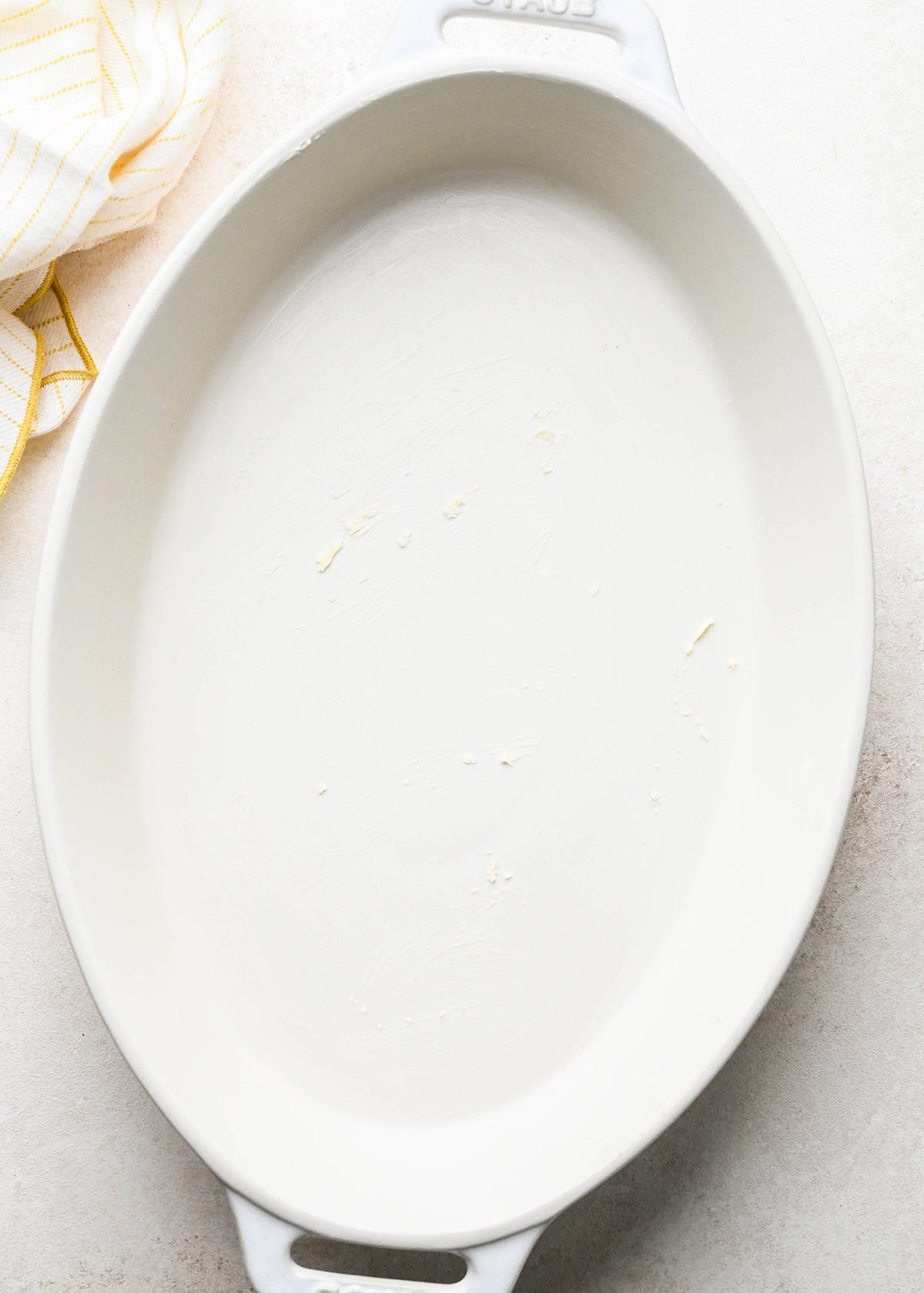 a buttered, white, oval baking dish