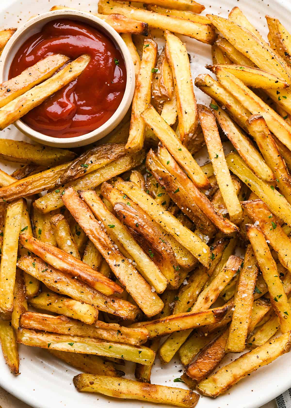 Homemade French Fries on a serving plate with a bowl of ketchup