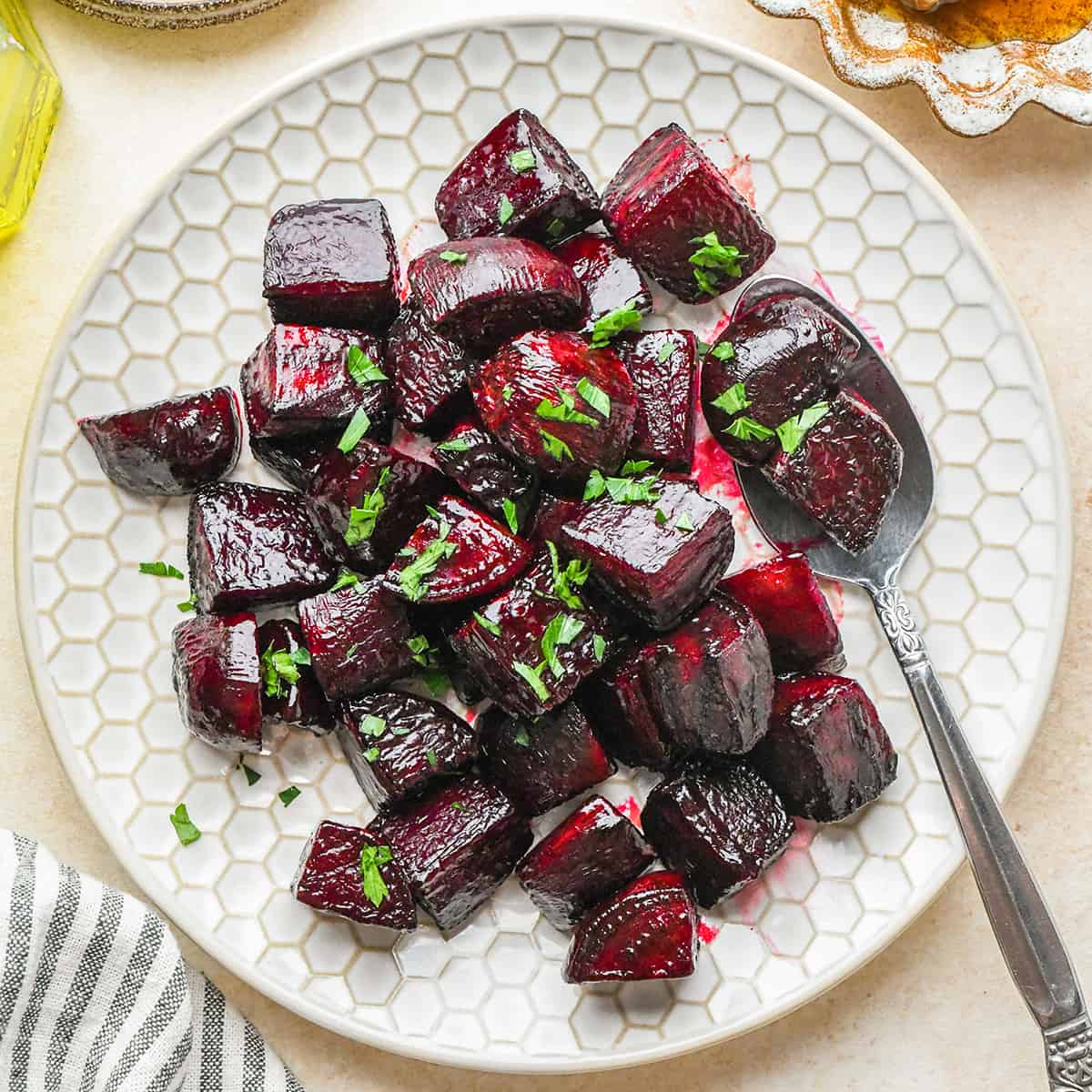 Oven Roasted Beets Recipe on a plate with a spoon garnished with greens