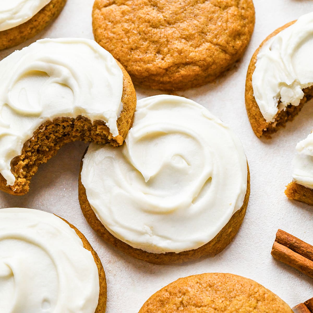 5 Pumpkin Cookies with Cream Cheese Frosting, one with a bite taken out of it