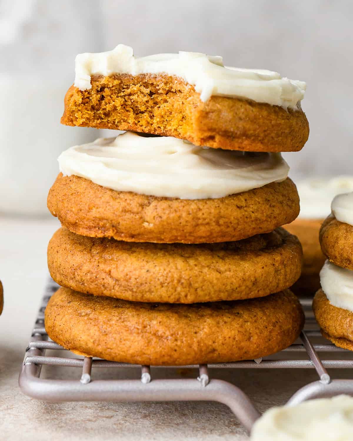  a stack of 4 Pumpkin Cookies with Cream Cheese Frosting, the top one has a bite taken out of it