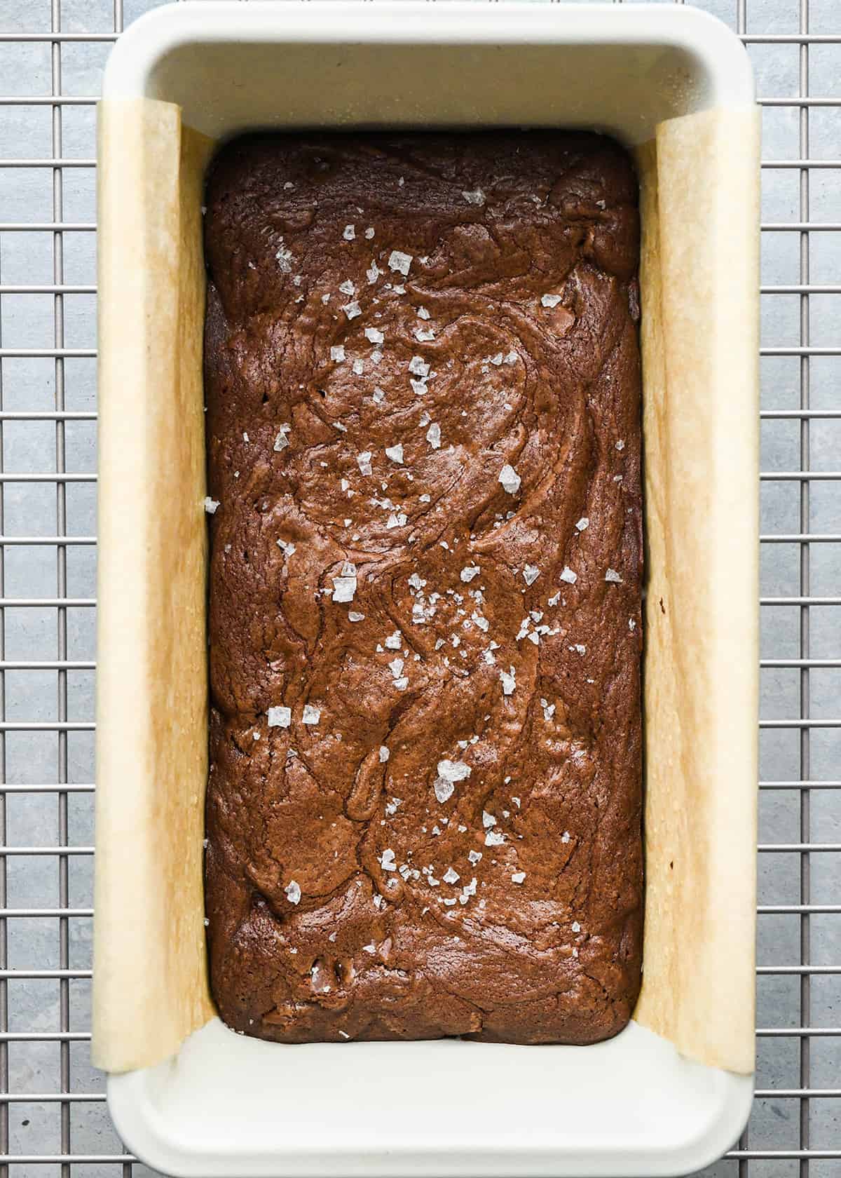 Small Batch Brownies in a loaf pan on a wire cooling rack with flaky sea salt on top