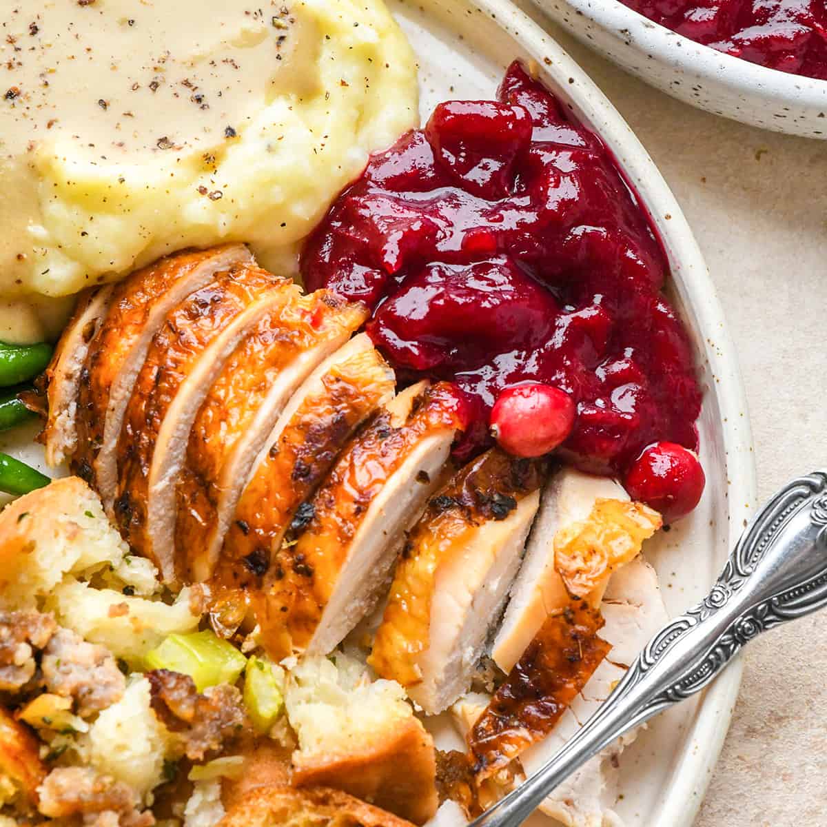 cranberry sauce on a plate with turkey, mashed potatoes, green beans and stuffing