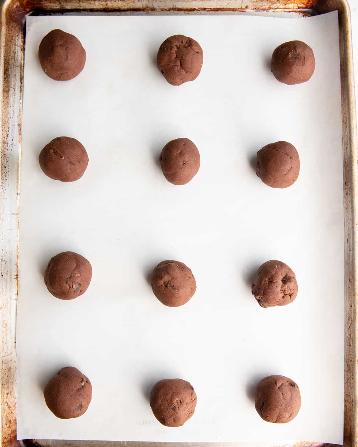 12 brownie cookie dough balls on a baking sheet before baking