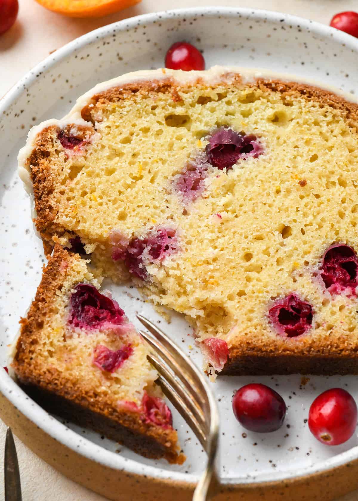 a piece of Cranberry Orange Bread on a plate with a fork taking a bite