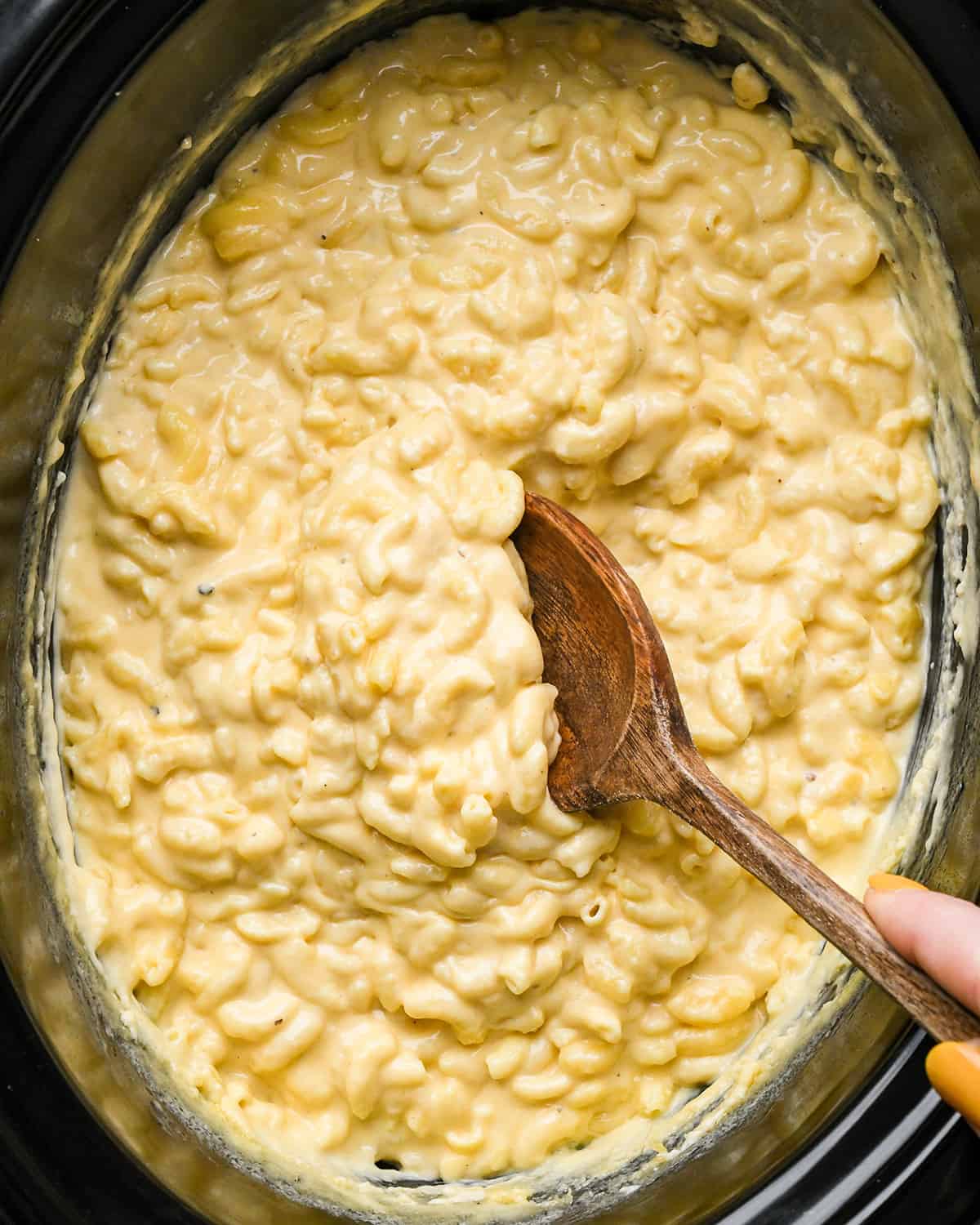 crock pot macaroni and cheese being stirred after cooking