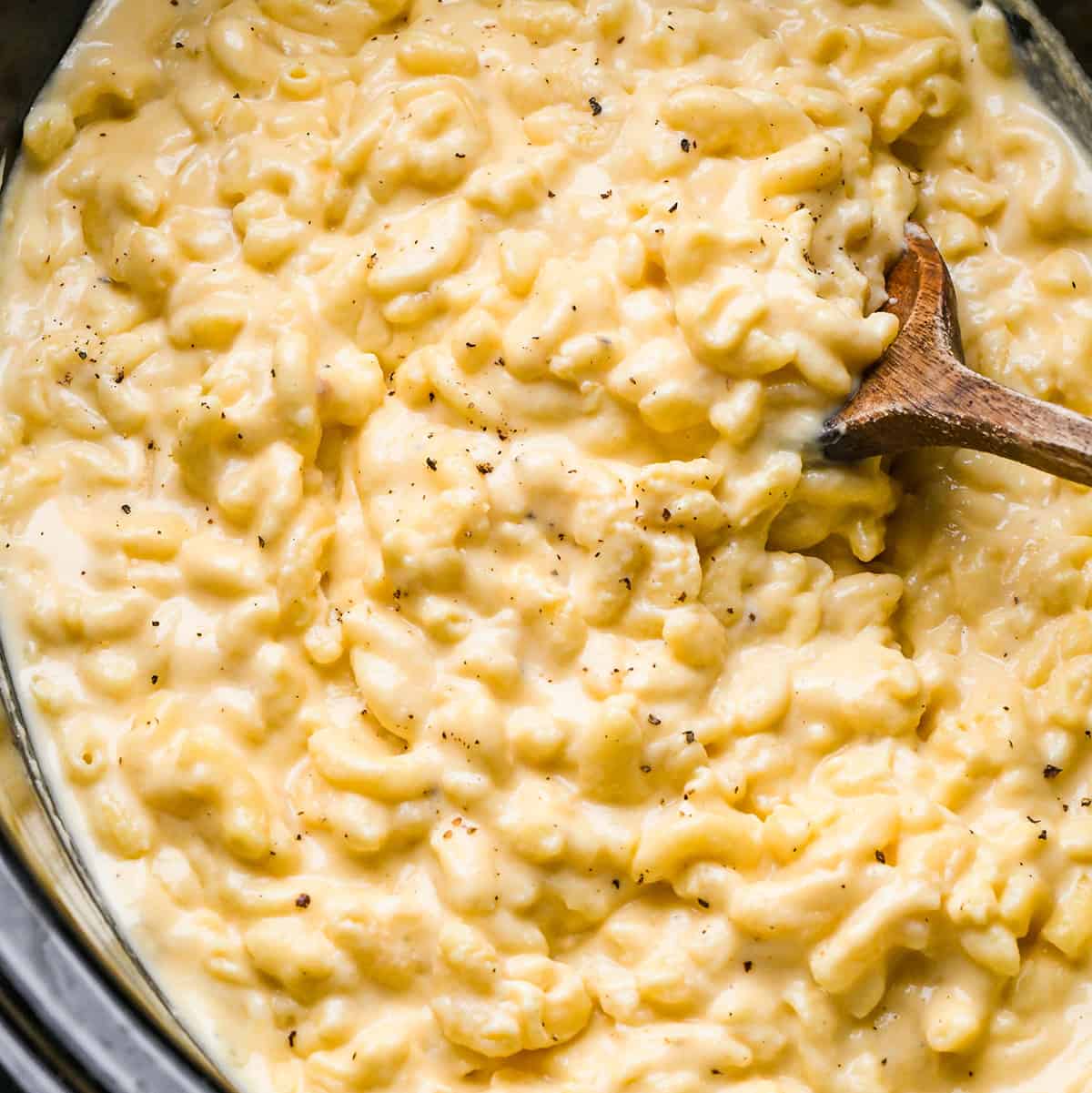 Crock Pot Mac and Cheese in a slow cooker with a wooden spoon