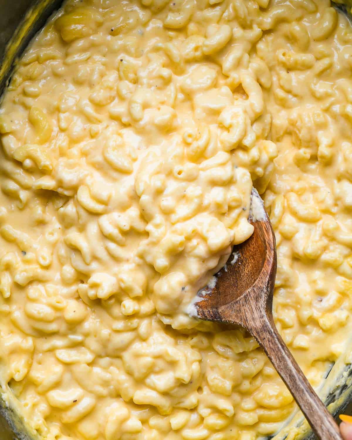 Crock Pot Mac and Cheese in a slow cooker with a wooden spoon