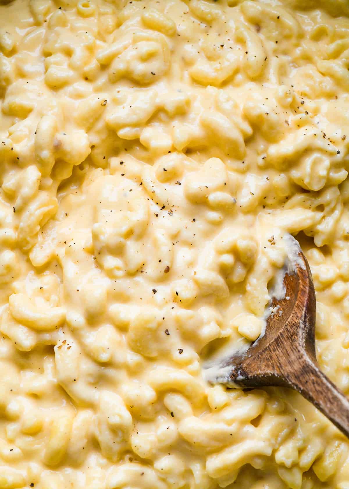 up close photo of Crock Pot Mac and Cheese with a wood spoon