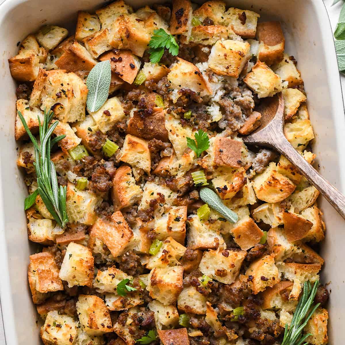 Homemade Stuffing in a baking dish with a wooden spoon