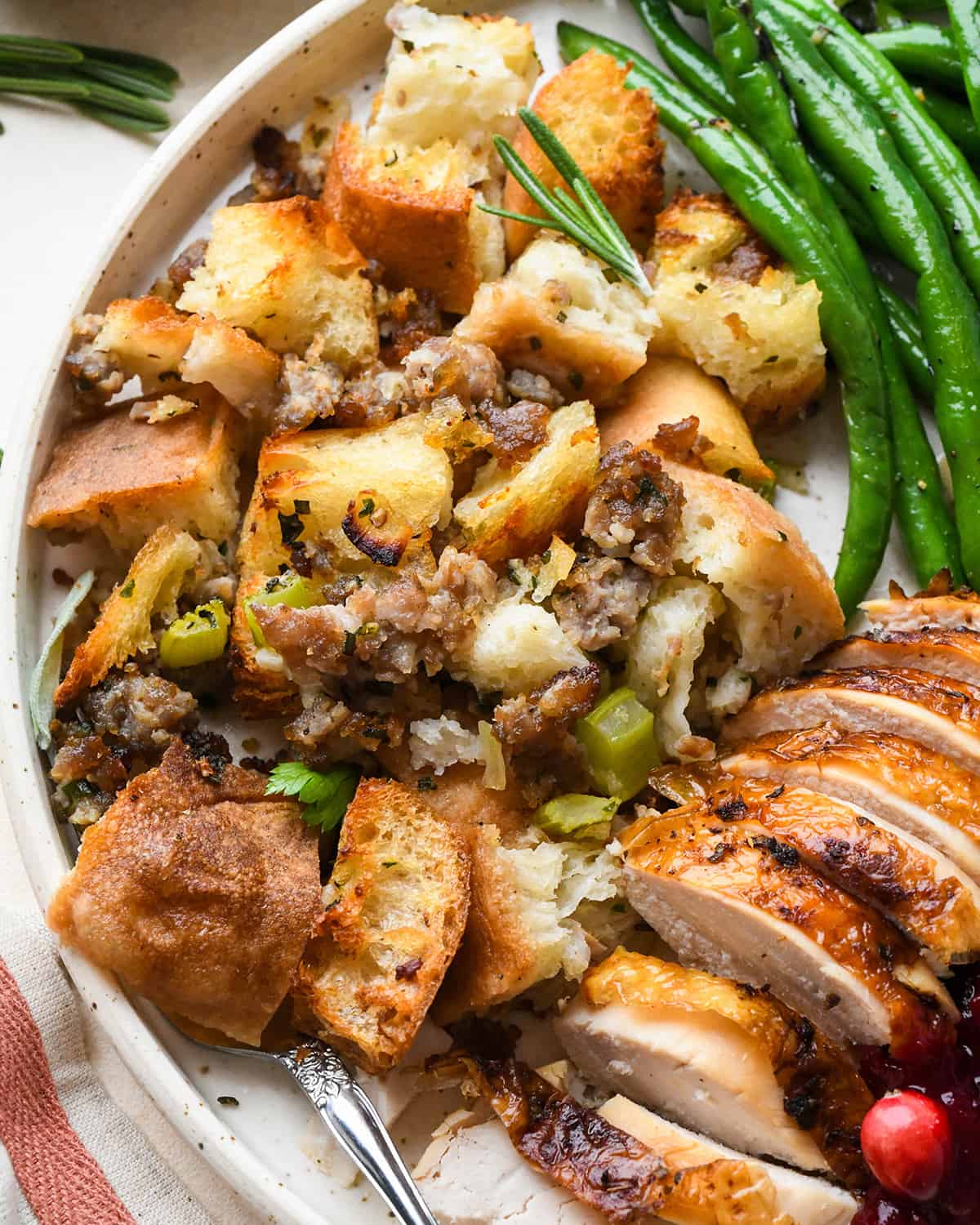 Homemade Stuffing on a plate with turkey, green beans and cranberry sauce