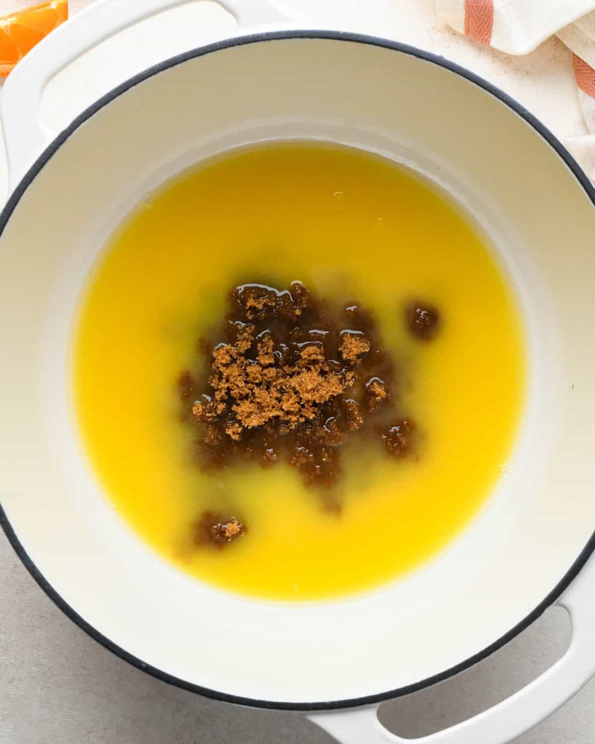 how to make cranberry sauce - both sugars added to orange juice in a white pot with a black rim before mixing