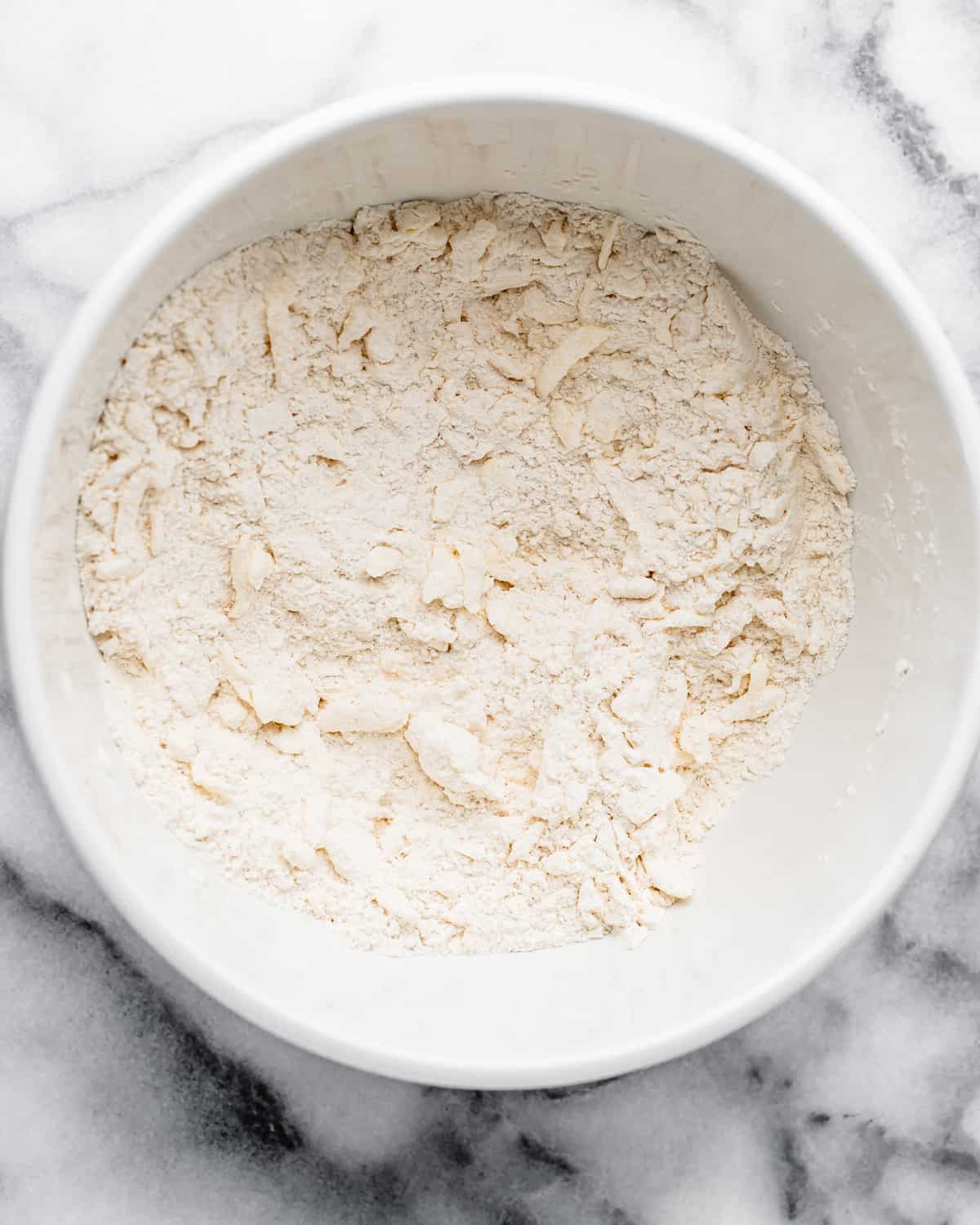 grated butter added to dry ingredients in a bowl after mixing