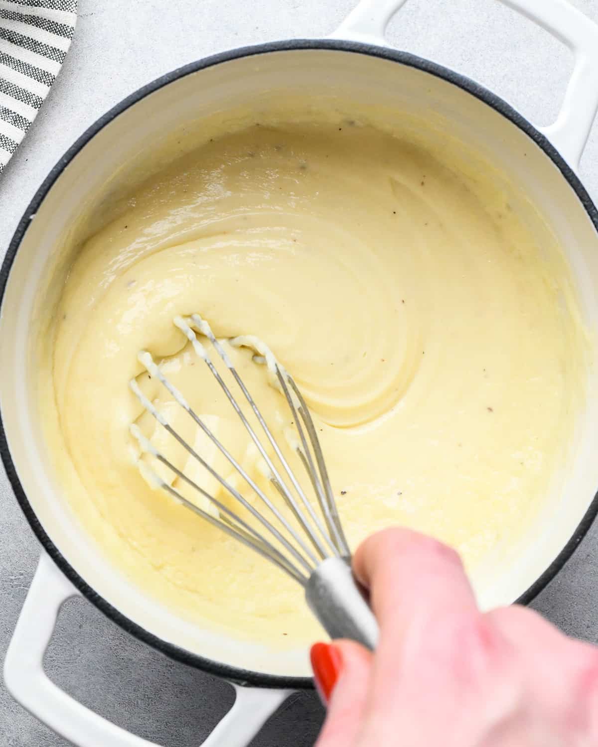 cheese fondue being whisked in a saucepan