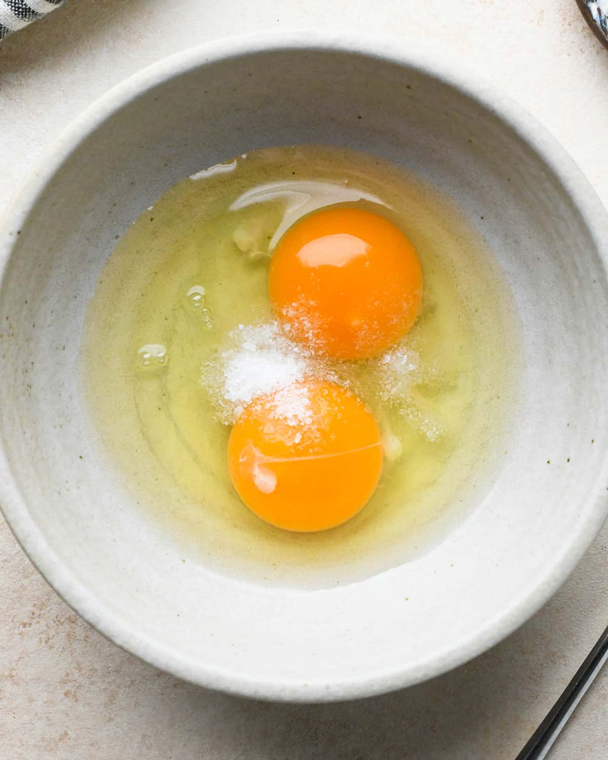 two eggs and salt in a bowl before beating