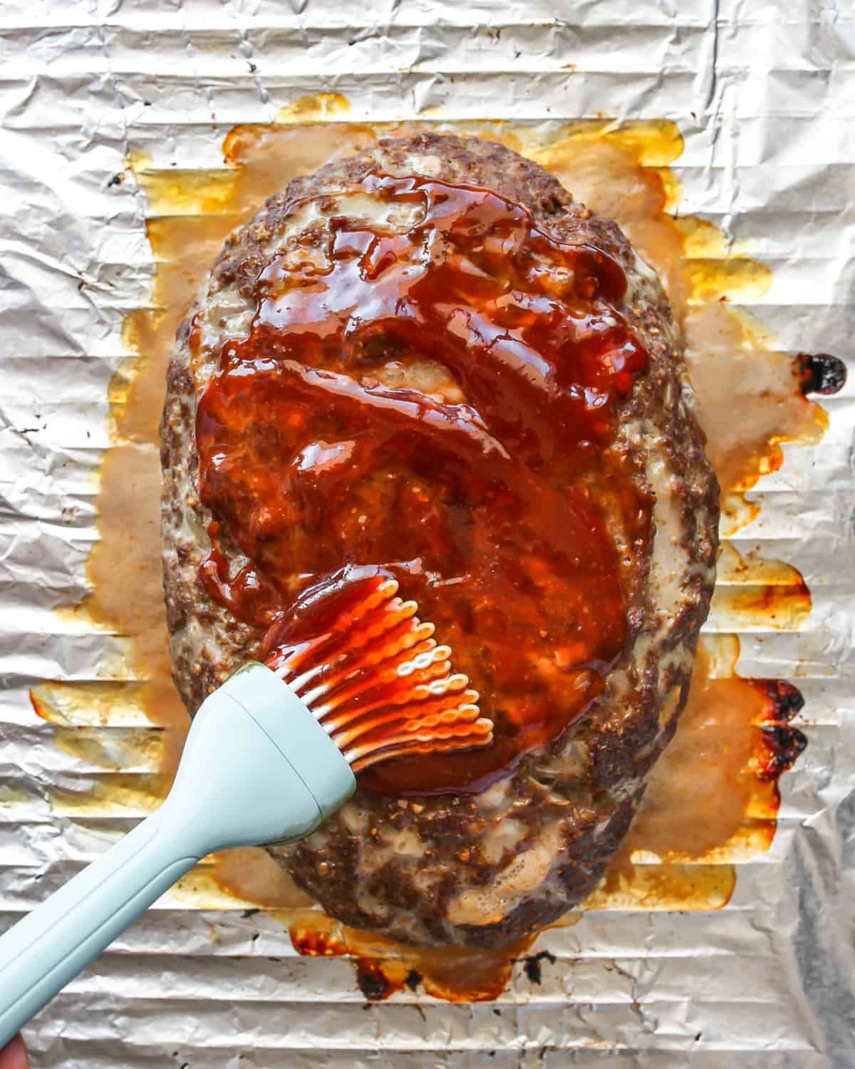 How to Make Meatloaf - brushing glaze on top of partially baked meatloaf with a pastry brush
