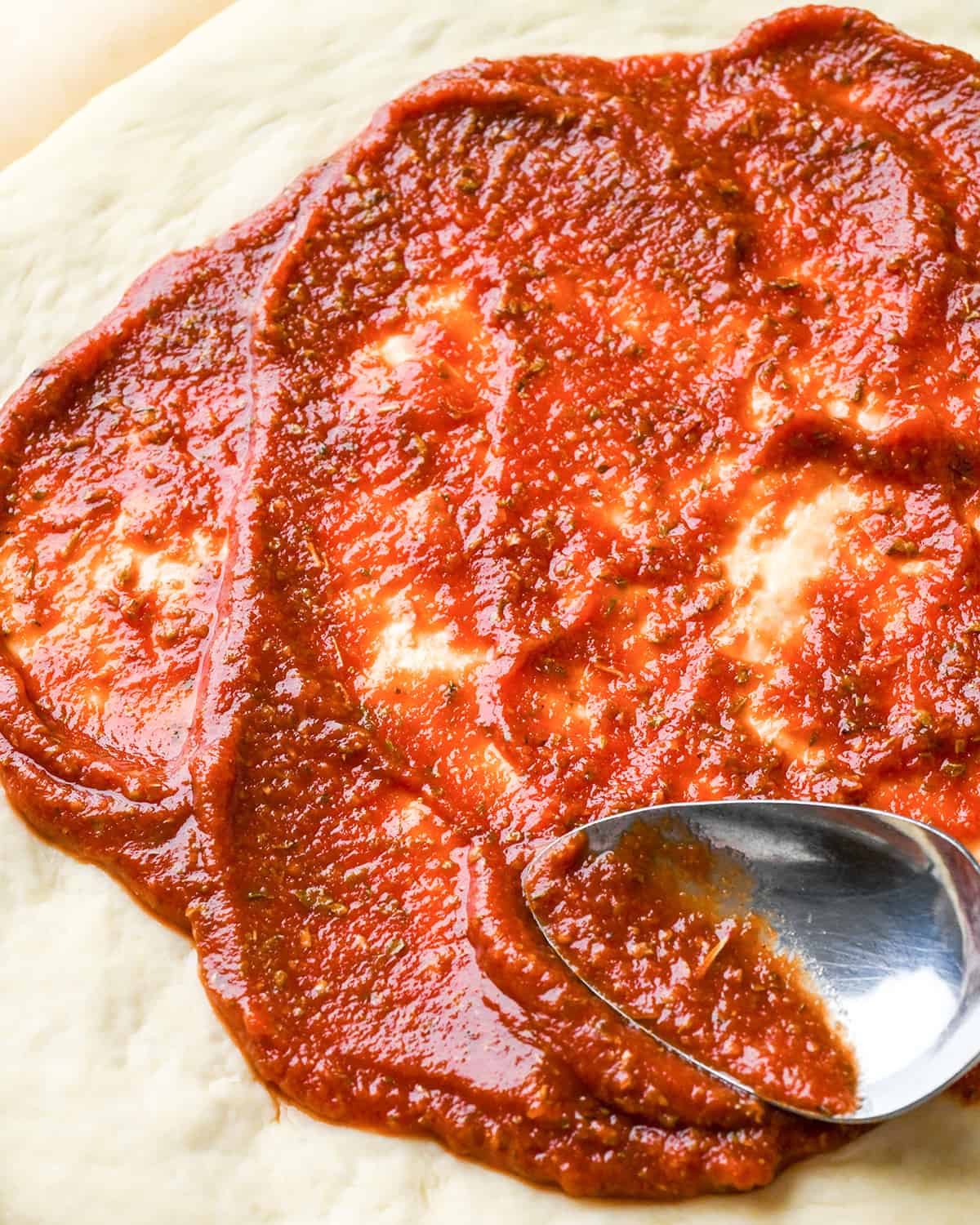 How to Make Pizza - spreading sauce on dough