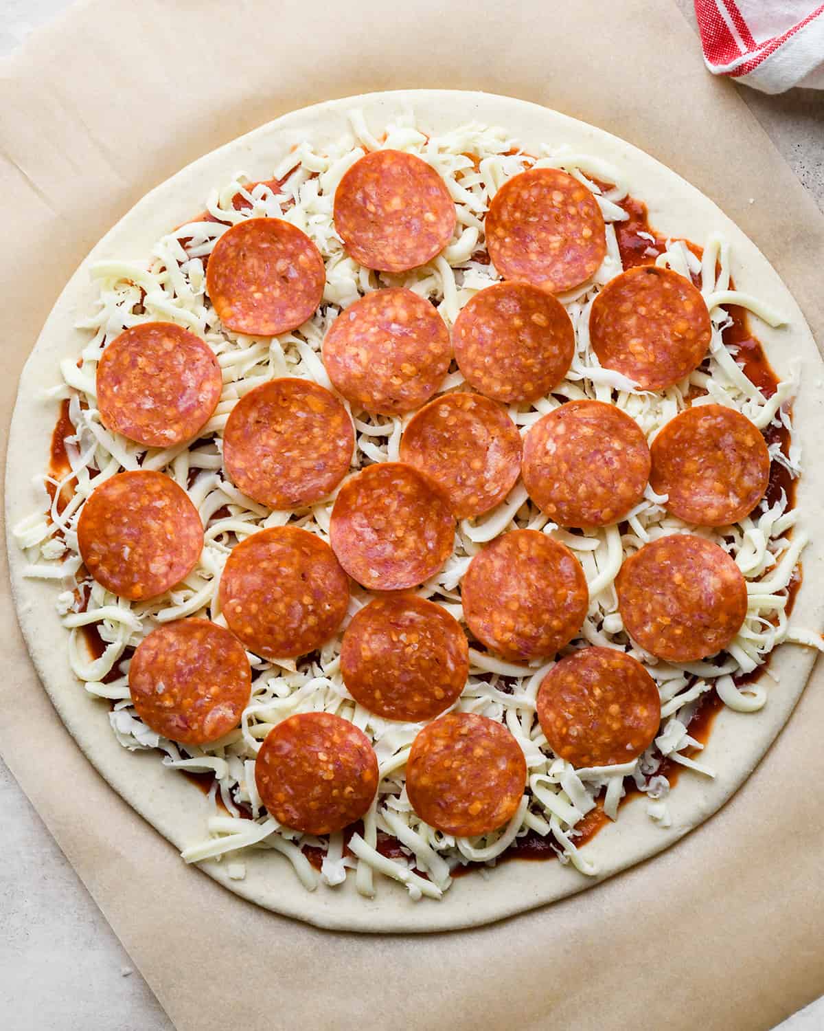 How to Make Pizza adding pepperoni on top of a layer of cheese
