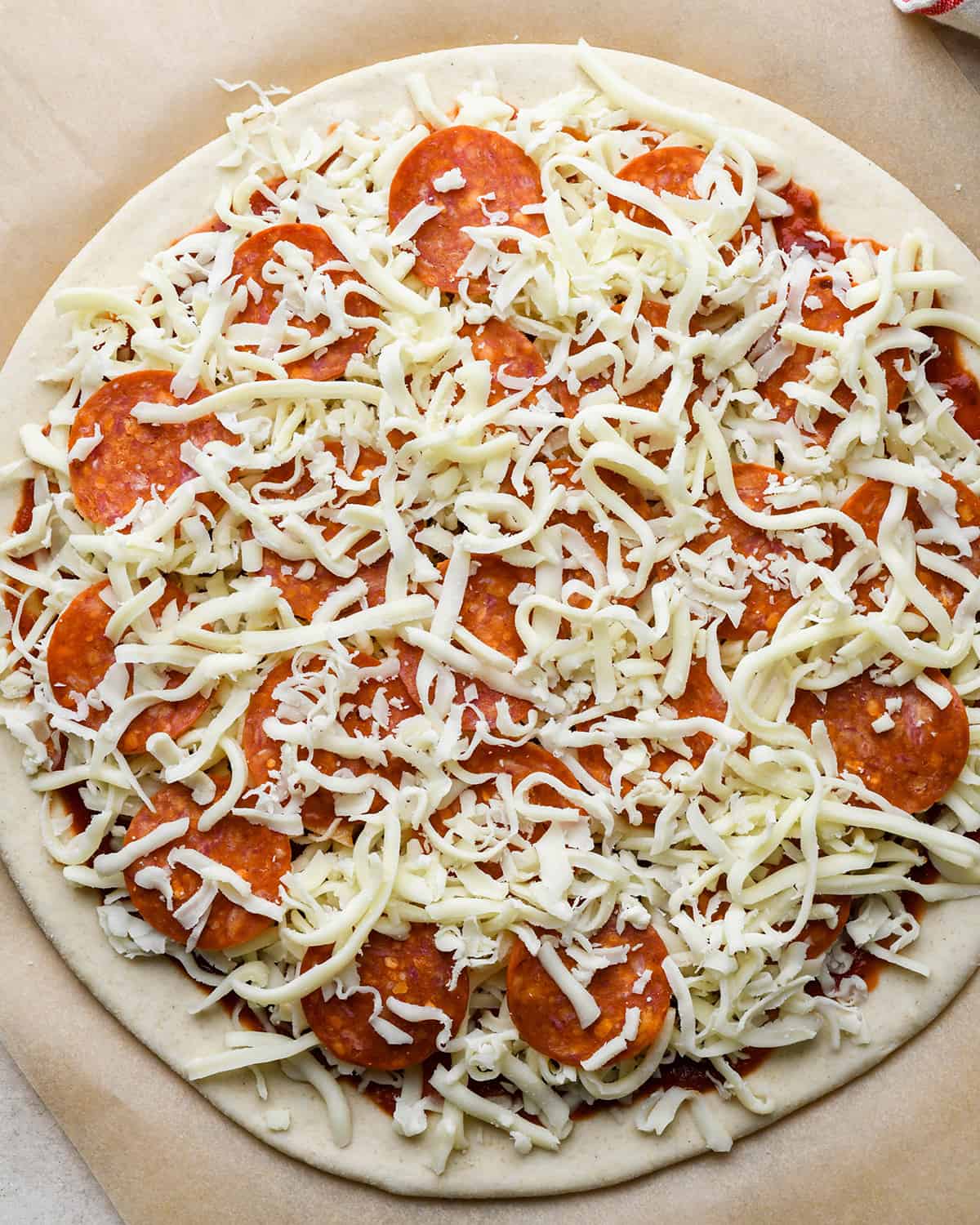 How to Make Pizza adding a layer of cheese over toppings