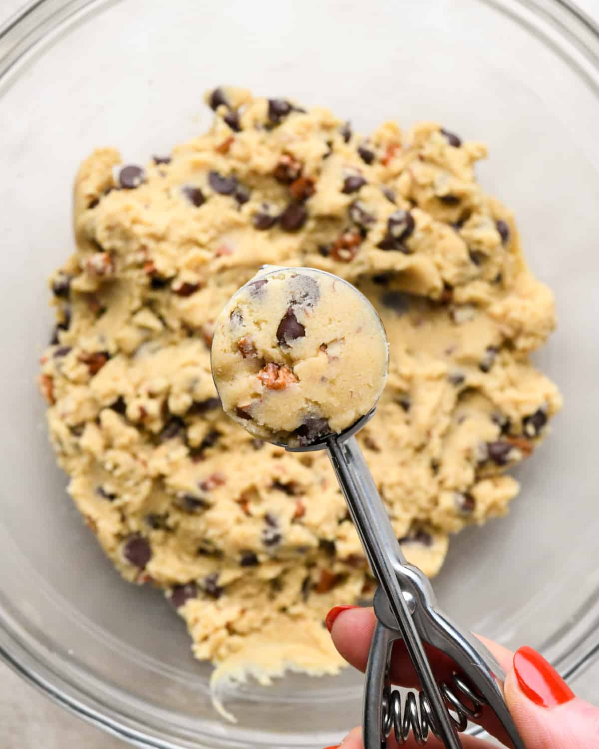 a cookie scoop measuring out a portion of pecan chocolate chip cookies dough