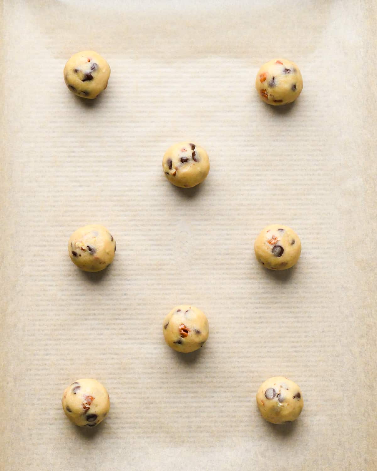 8 Chocolate Chip Pecan Cookie dough balls on a baking sheet before baking