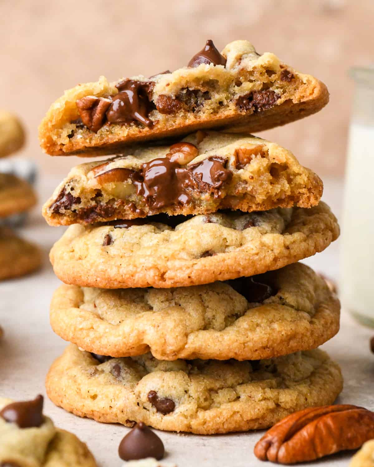 a stack of 4 Chocolate Chip Pecan Cookies, the top one is cut in half so the middle is showing