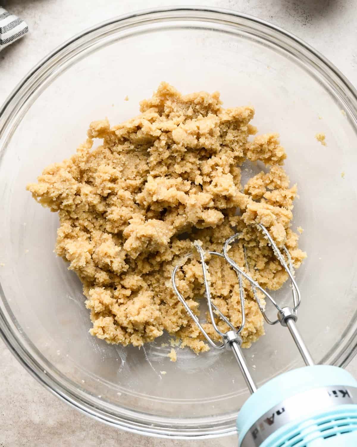 butter, white sugar and brown sugar in a bowl with a handheld mixer after mixing