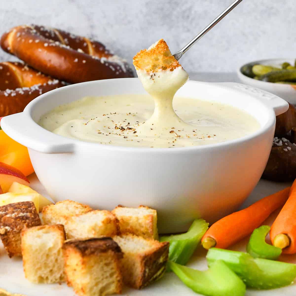 a piece of toasted bread dipped into Cheese Fondue in a bowl