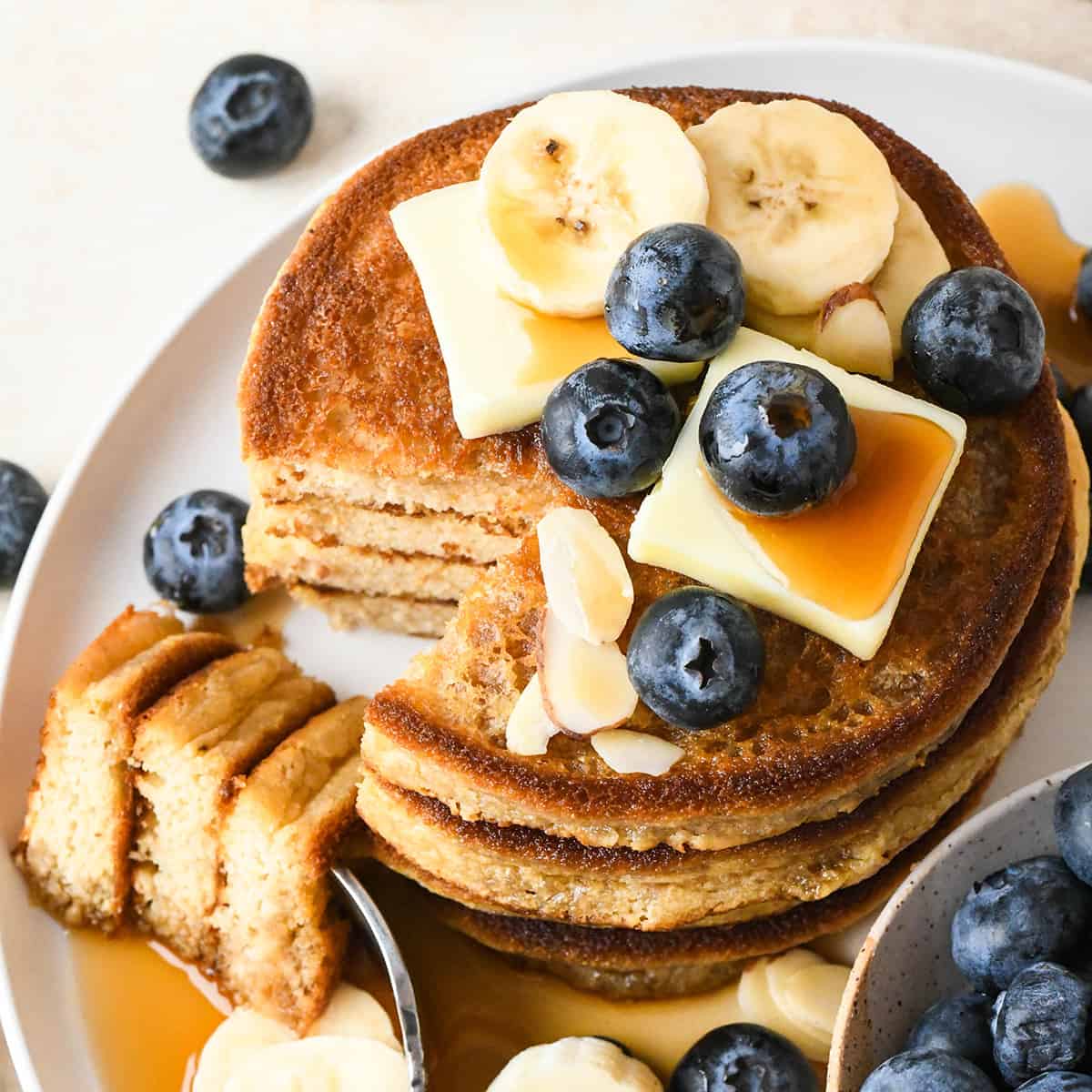 une pile de 3 crêpes à la farine d'amande avec une bouchée coupée sur une fourchette