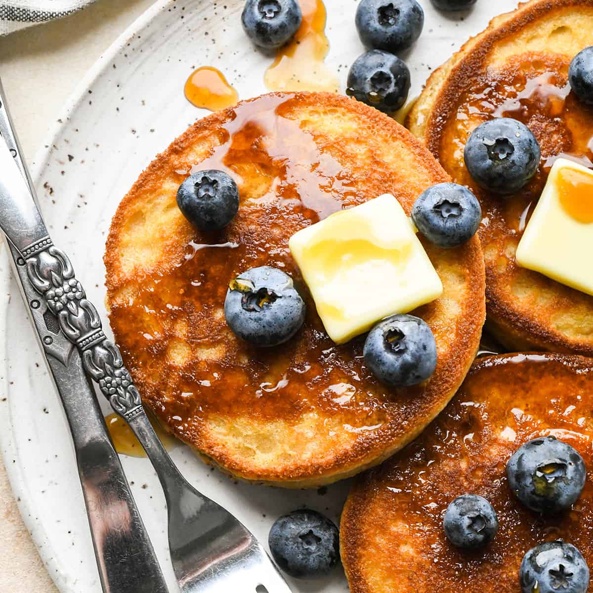 3 Almond Flour Pancakes on a plate with syrup, butter and blueberries