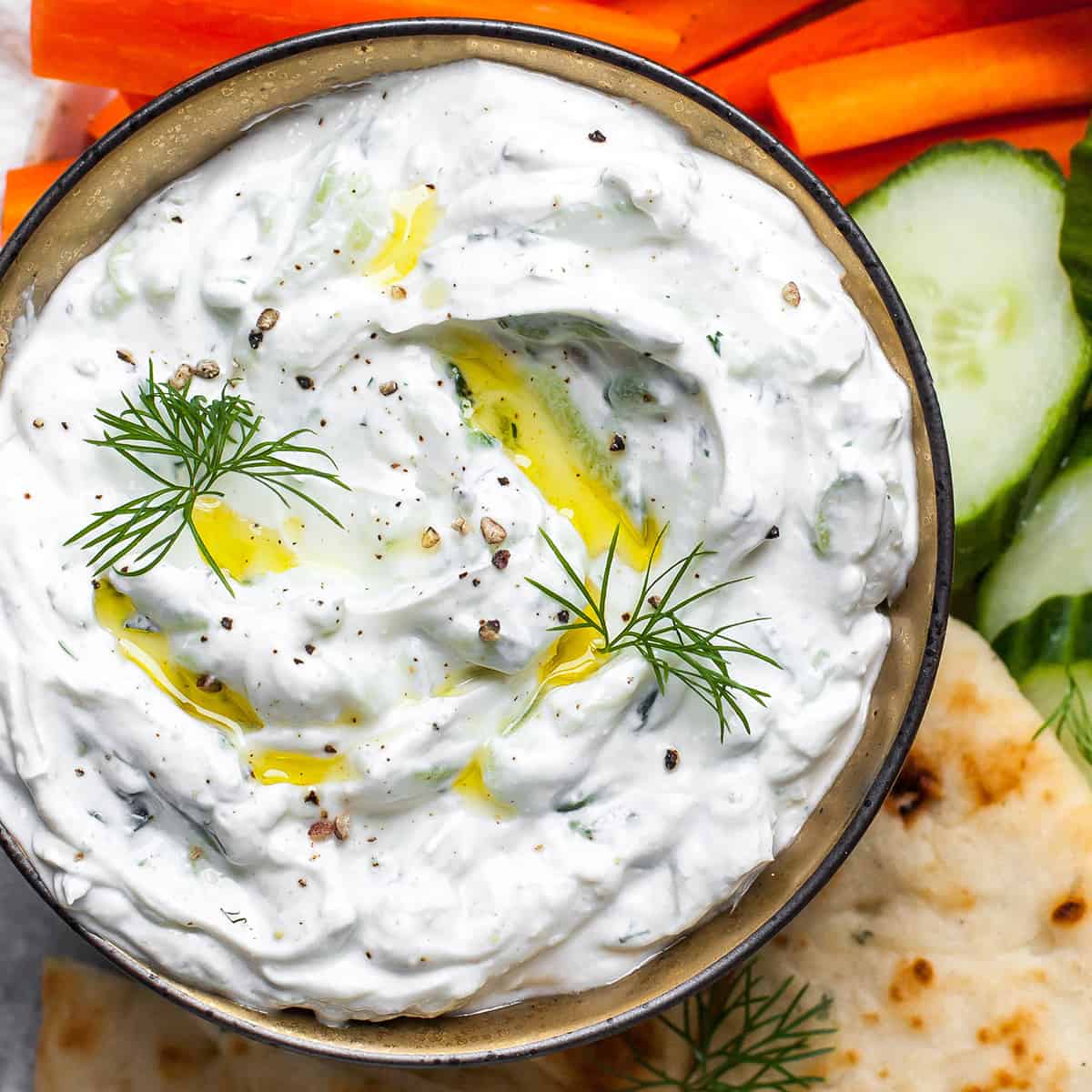 Homemade Tzatziki Sauce in a bowl garnished with olive oil, dill and black pepper