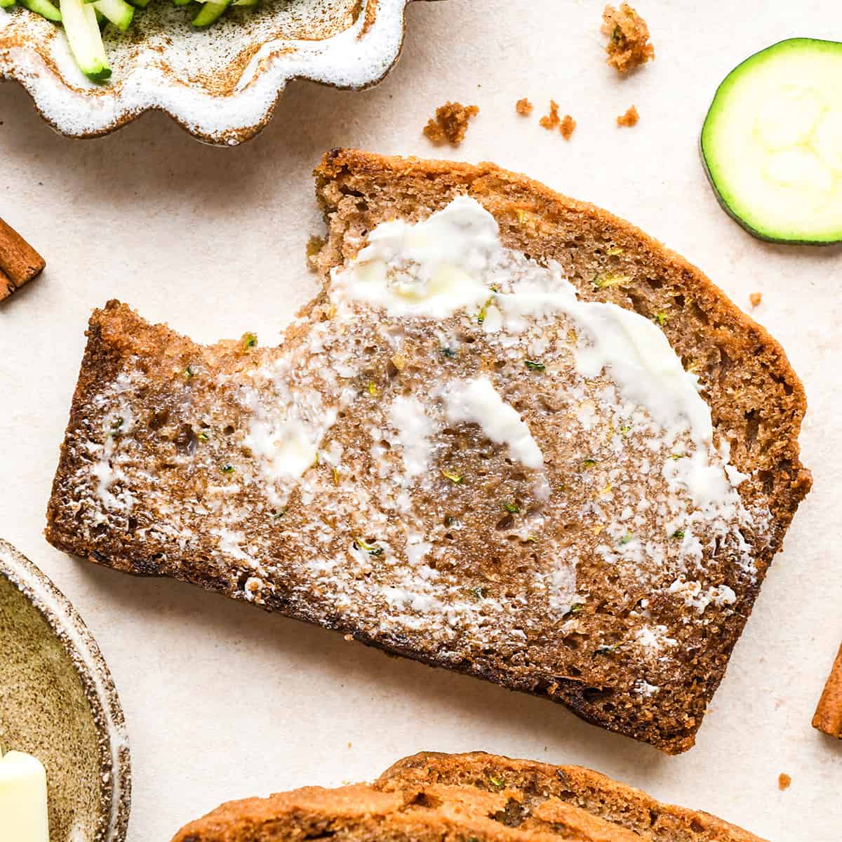 a slice of Zucchini Bread with butter spread on it and a bite taken out of it