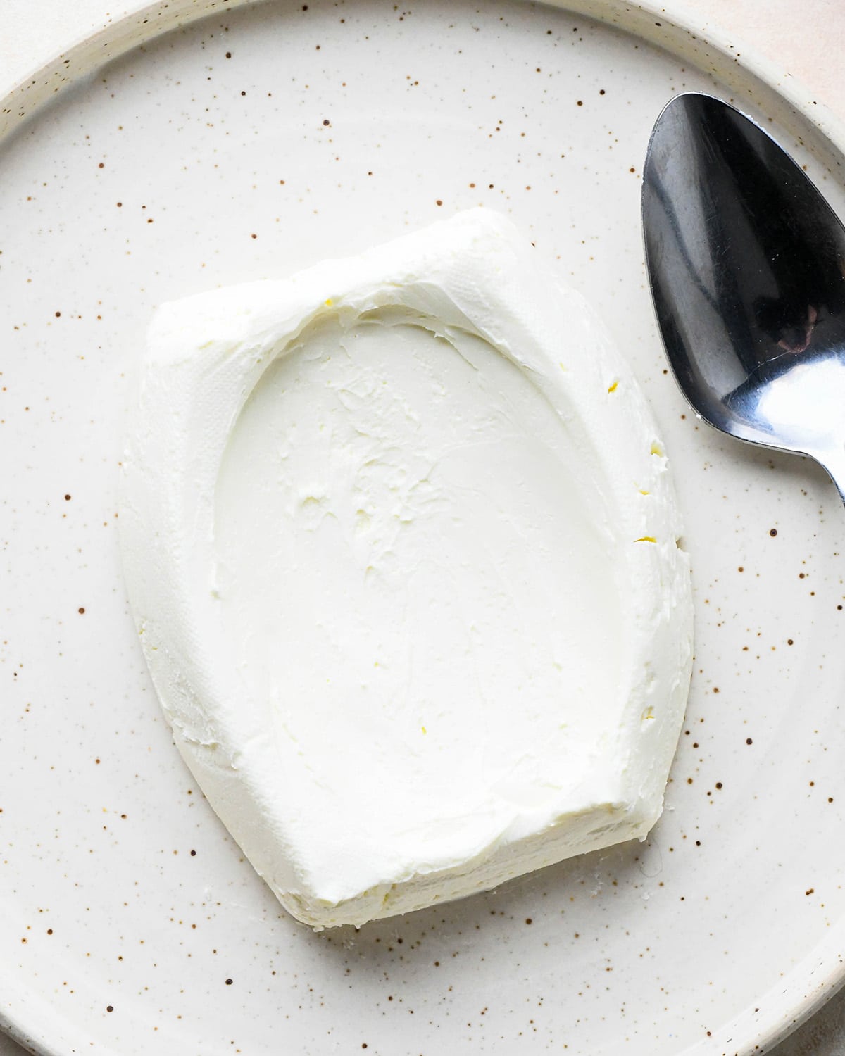 a block of cream cheese on  a plate with an indentation in it