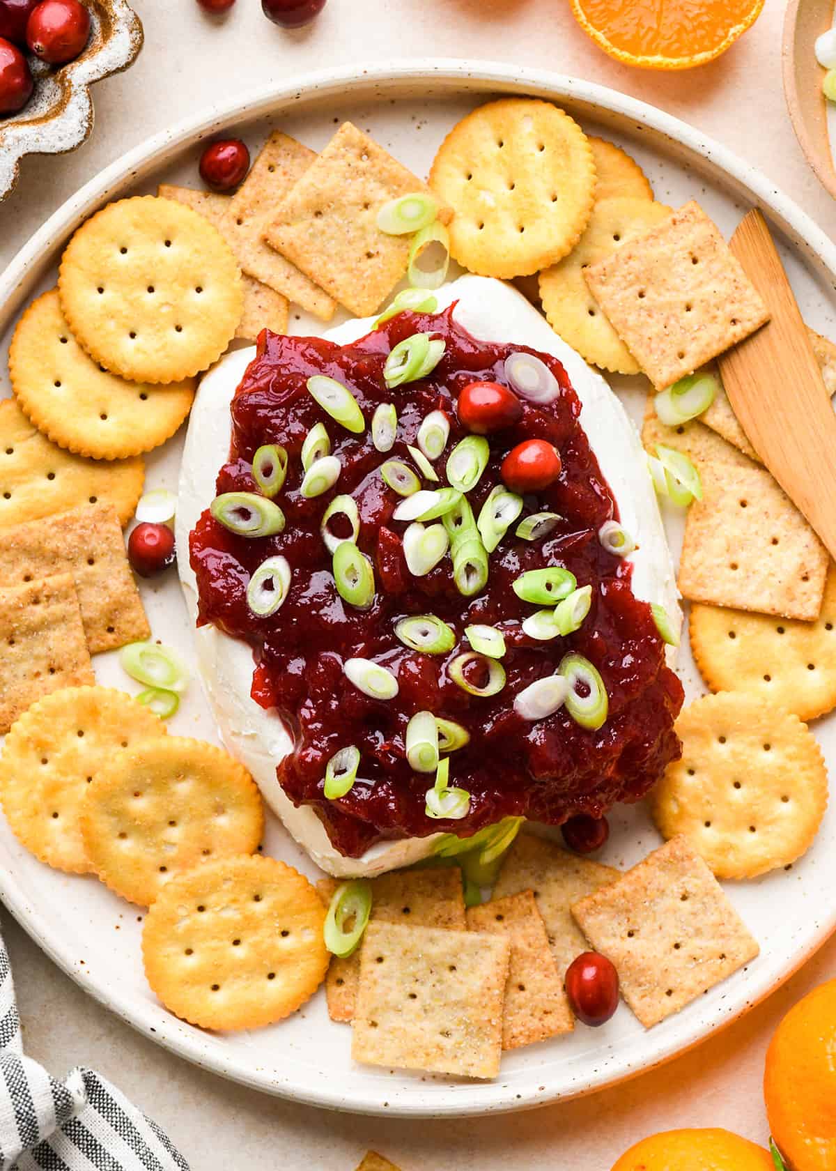 Cranberry Cream Cheese Dip topped with green onions on a serving plate surrounded by crackers