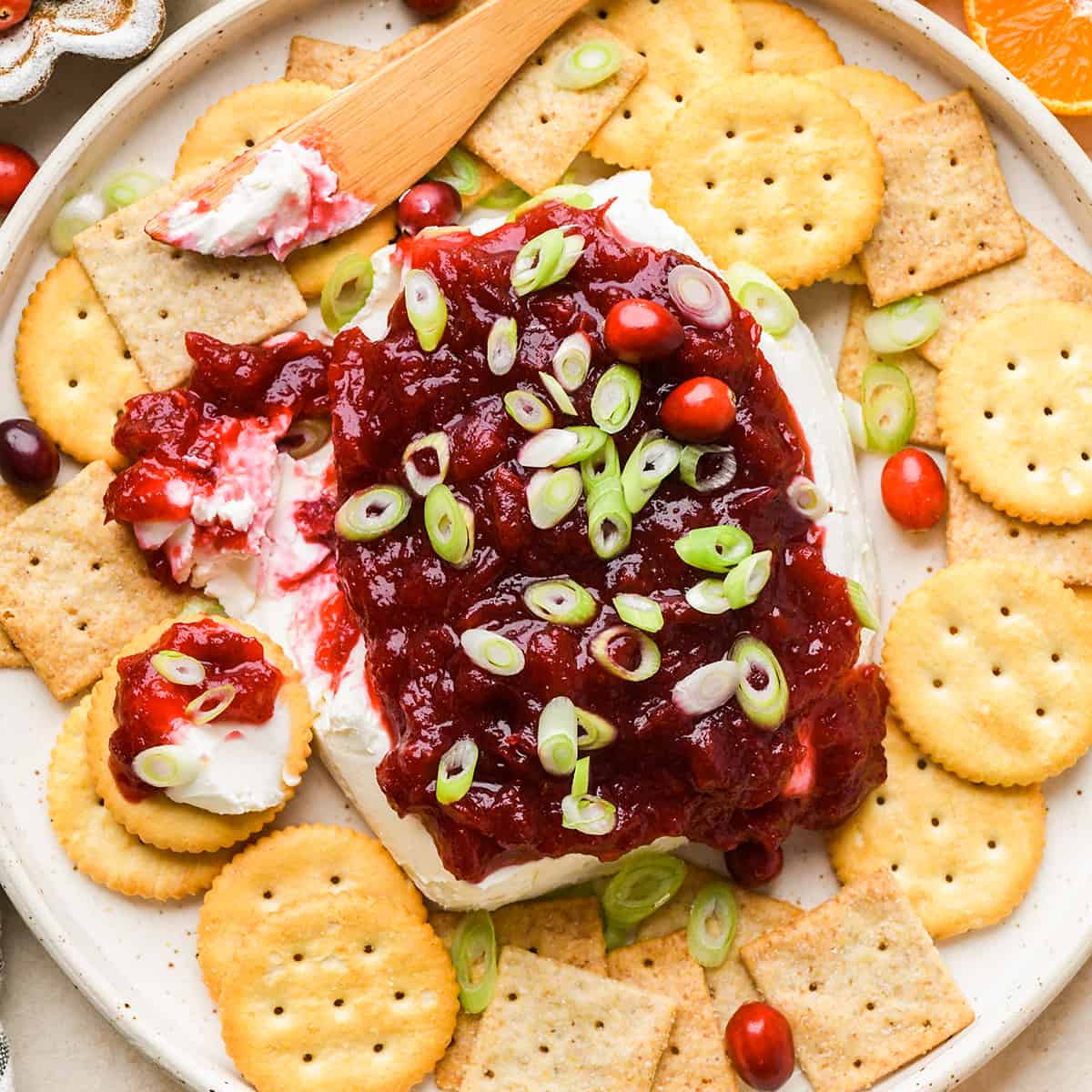 Cranberry Cream Cheese Dip with a knife that has spread some onto crackers 