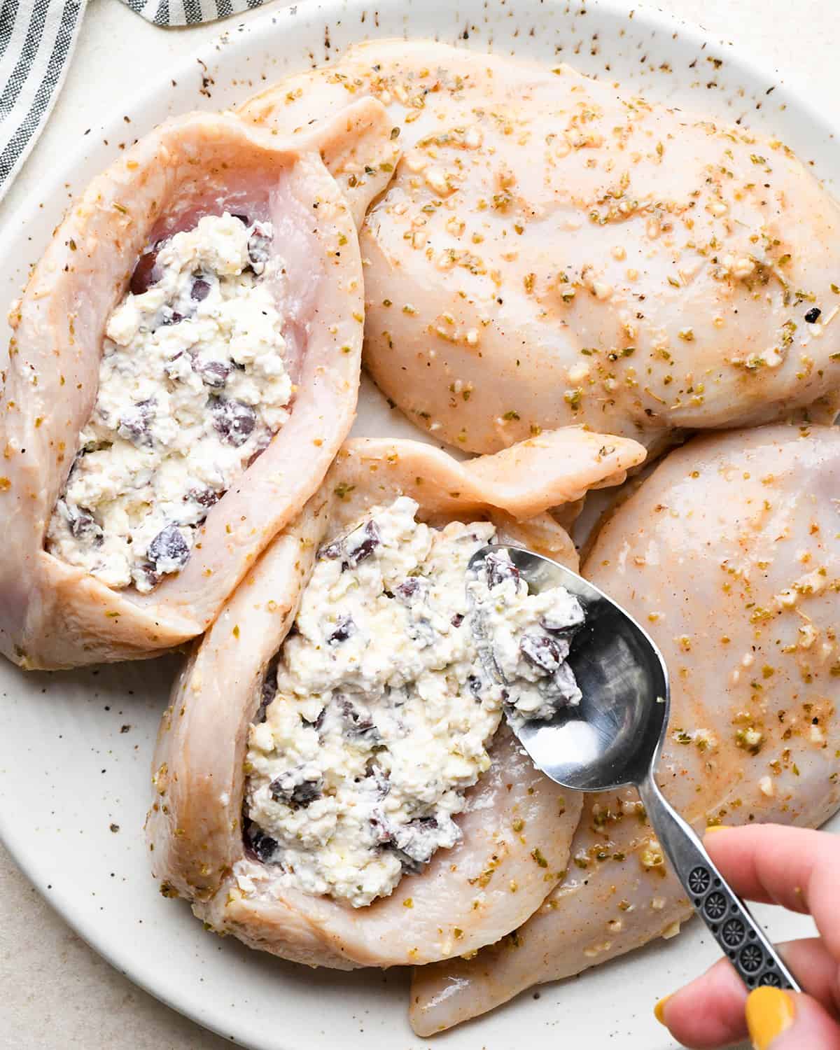 a spoon adding the filling to a chicken breast